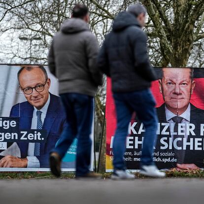 Top candidates for the upcoming German federal Bundestag elections, Friedrich Merz of the CDU, left, and German chancellor Olaf Scholz of the SPD, right, watch from election posters at a street in Duesseldorf, Germany, Tuesday, Feb. 11, 2025. (AP Photo/Martin Meissner)