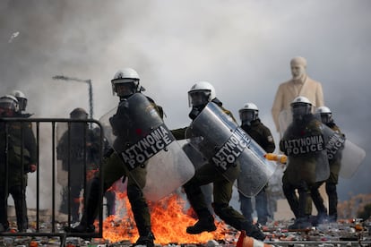 Agentes de policía se protegen durante los enfrentamientos con los manifestantes cerca del Parlamento de Grecia en Atenas, este viernes.