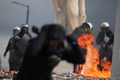 Dos agentes antidisturbios reaccionan ante el lanzamiento de un cóctel molotov frente al Parlamento de Grecia.