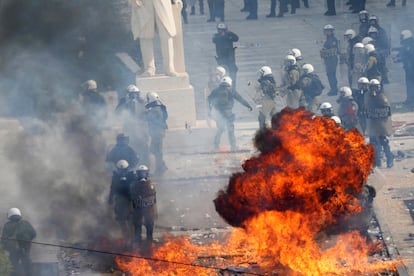 La policía antidisturbios intenta evitar las llamas de un cóctel molotov frente al Parlamento.