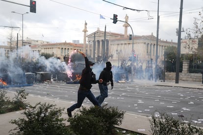 Un manifestante lanza una bengala a los agentes antidisturbios durante la protesta en Atenas.