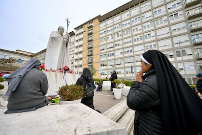 Varias monjas rezan ante la escultura de Juan Pablo II situada frente al hospital Gemelli de Roma, donde está ingresado el papa Francisco, este miércoles.