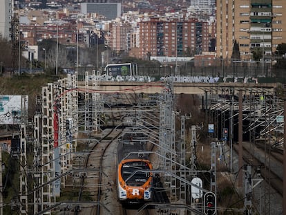 Un tren de Rodalies Renfe de la linia R2 circula por las vías del tren a su paso por la Zona Franca, de fondo, la Area Metropolitana de Barcelona.