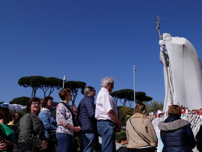 Un grupo de personas rezan ante la estatua de Juan Pablo II situada frente al hospital Gemelli de Roma, este miércoles.