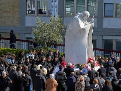 Un grupo de fieles reza alrededor de la estatua de Juan Pablo II en el exterior del Policlínico Agostino Gemelli, donde está hospitalizado el papa Francisco, en Roma, este domingo.