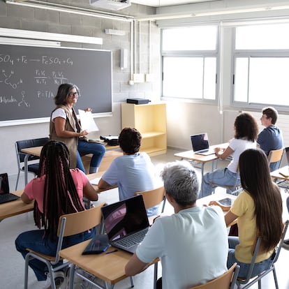 High angle view of mature female teacher explaining lesson to multiracial high school students in class. Back to school concept.
