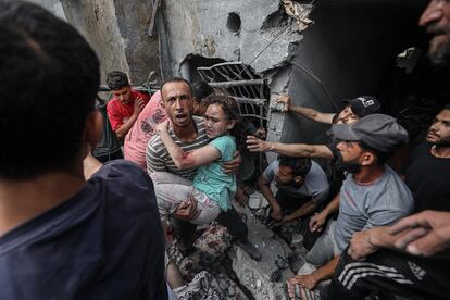 Un miembro de los equipos de rescate transporta a una niña herida en un bombardeo sobre el campo de refugiados de Yabalia, en el norte de Gaza, este domingo.