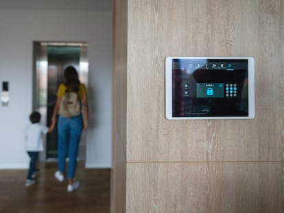 Una madre sale de casa con su hijo tras poner la alarma.